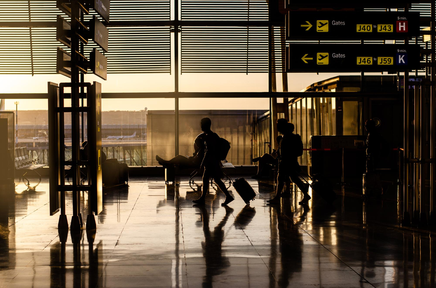 Viajantes com malas em um aeroporto iluminado pelo sol